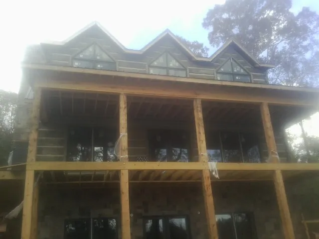 Dormers and porch framing on a large log home under construction — Roof Coating work by our crew in Rochdale