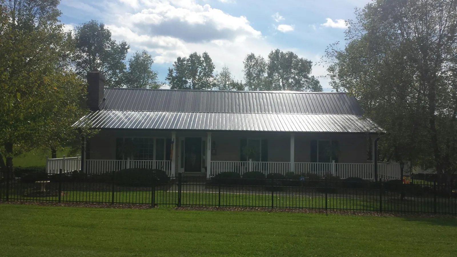 Gray metal roof on a brick ranch with a full width front porch — Gutter Guard Installation work by our crew in Rochdale