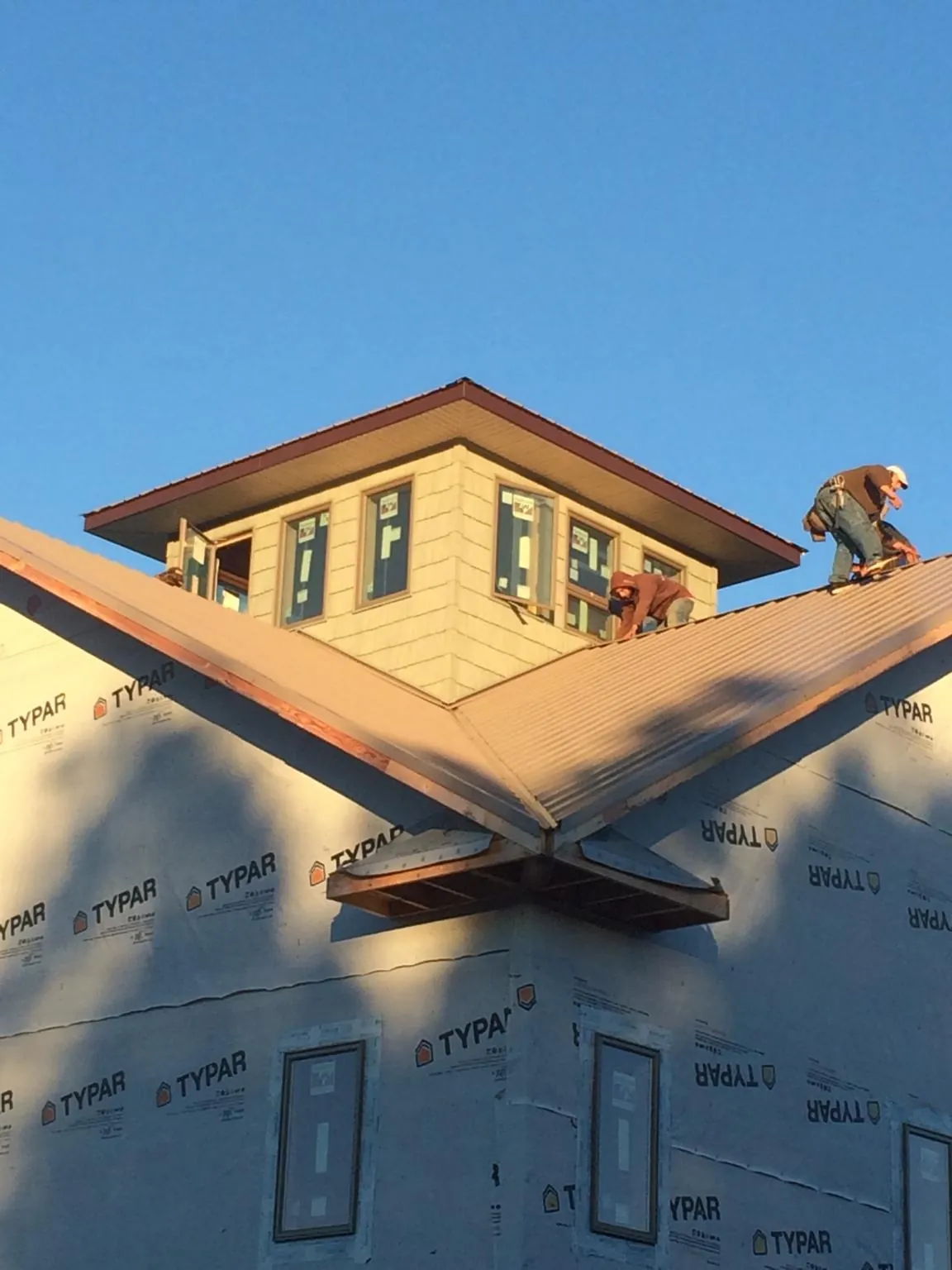 Roofers working around a rooftop cupola on a new metal roof at sunset — Roof Waterproofing in Rochdale by Roofing Brothers